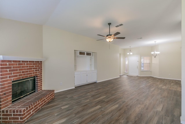 unfurnished living room with a brick fireplace, ceiling fan with notable chandelier, and dark hardwood / wood-style floors