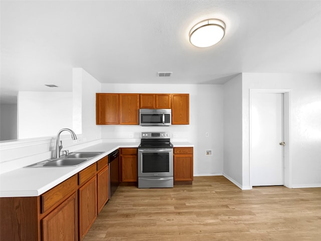 kitchen featuring kitchen peninsula, sink, light hardwood / wood-style flooring, and appliances with stainless steel finishes