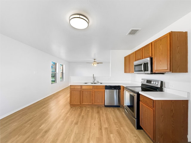 kitchen with ceiling fan, sink, stainless steel appliances, light hardwood / wood-style flooring, and kitchen peninsula