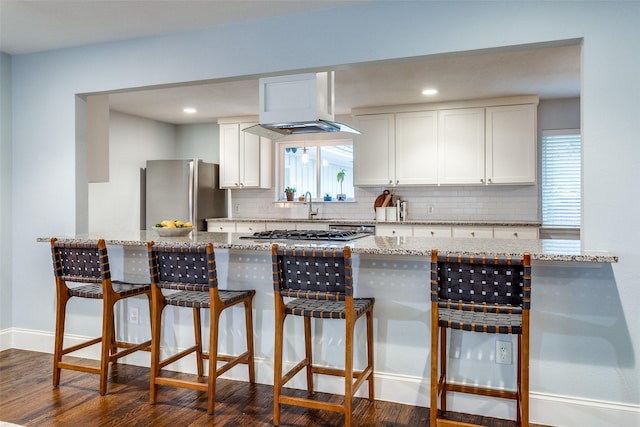 kitchen with white cabinetry, dark hardwood / wood-style flooring, decorative backsplash, stainless steel appliances, and light stone countertops