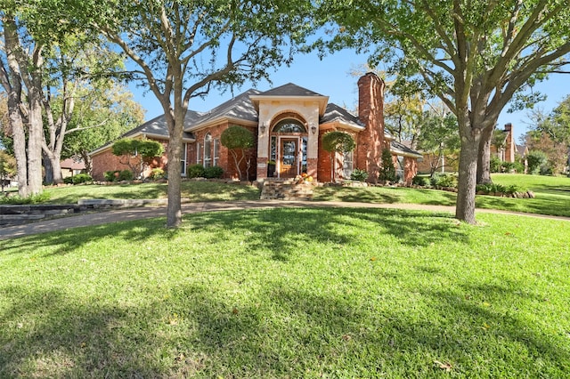 view of front of property with a front lawn, brick siding, and a chimney