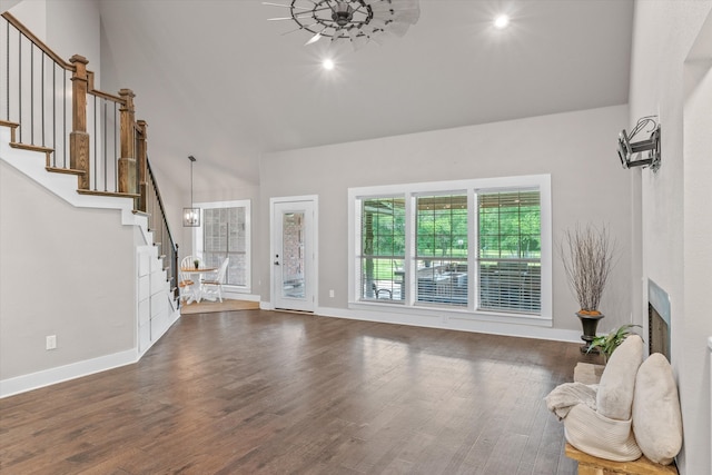 living room featuring dark hardwood / wood-style flooring, a towering ceiling, and a notable chandelier