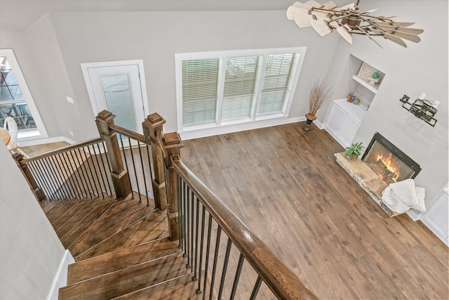 staircase with wood-type flooring and an inviting chandelier