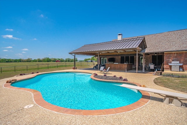 view of pool with area for grilling, a diving board, a patio area, and an outdoor bar