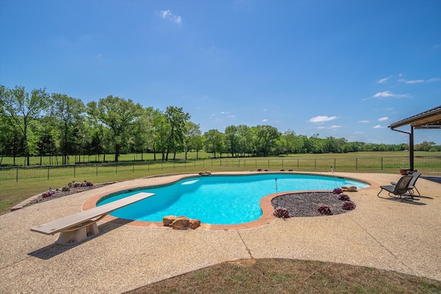 view of swimming pool featuring a patio area, a diving board, and a yard