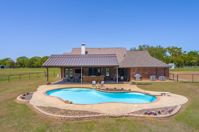 view of swimming pool featuring a diving board, an outdoor bar, a yard, area for grilling, and a patio area