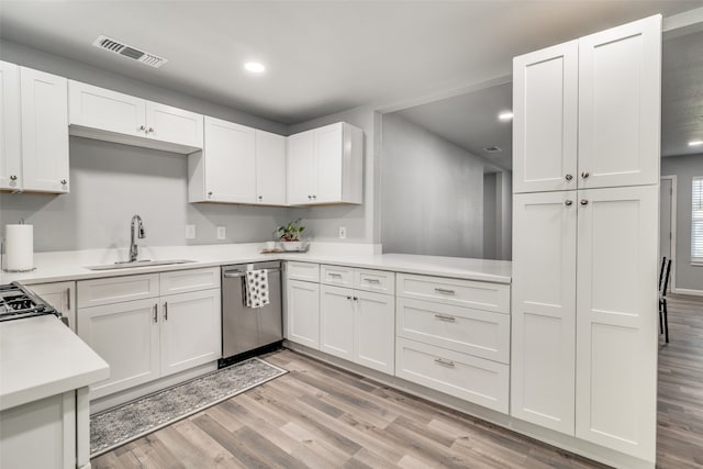 kitchen with sink, white cabinets, stainless steel dishwasher, and light wood-type flooring