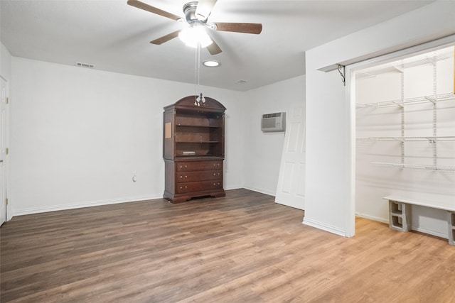 unfurnished bedroom featuring ceiling fan, wood-type flooring, a wall mounted AC, and a closet