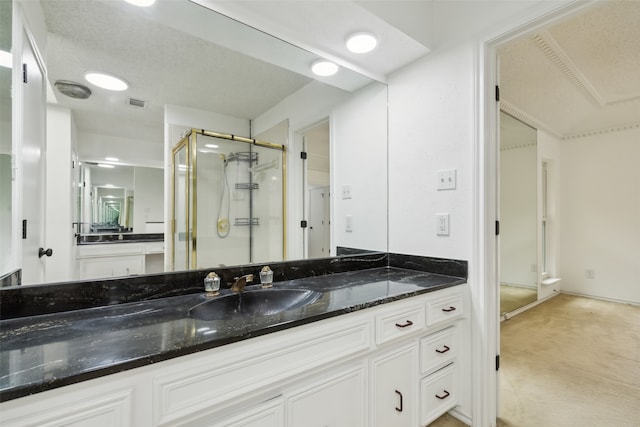 bathroom featuring a shower with door, vanity, and a textured ceiling