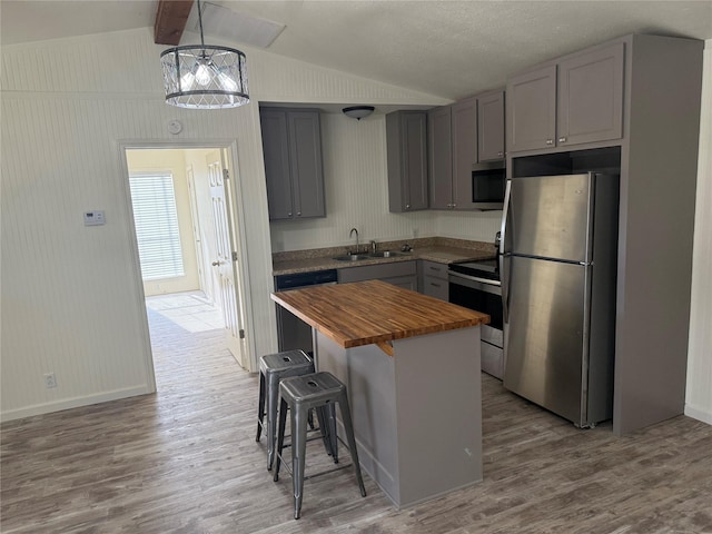 kitchen with wood counters, gray cabinetry, hanging light fixtures, appliances with stainless steel finishes, and a kitchen island