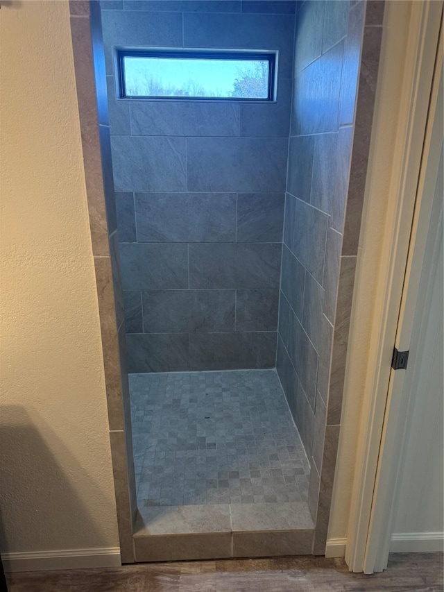 bathroom with a tile shower and hardwood / wood-style floors