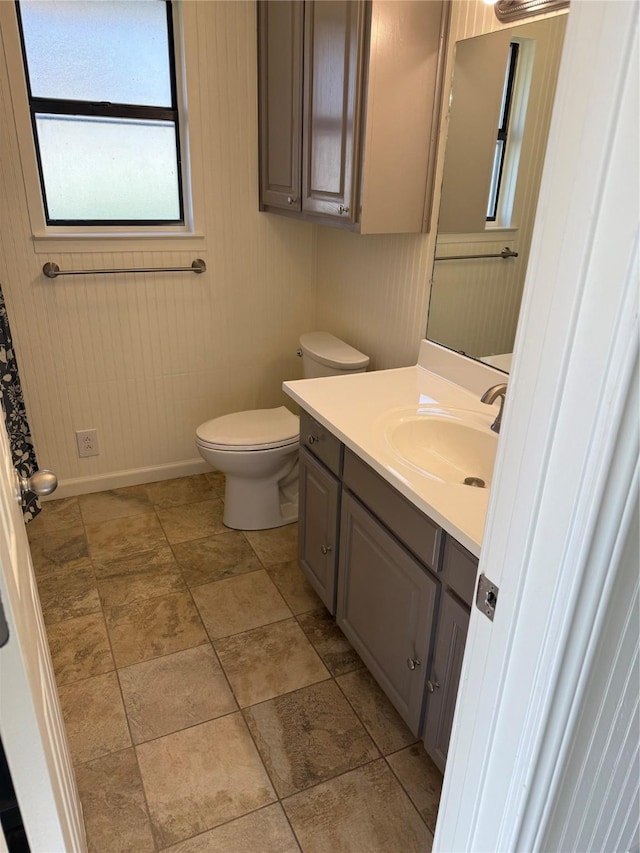 bathroom with vanity, toilet, and wooden walls