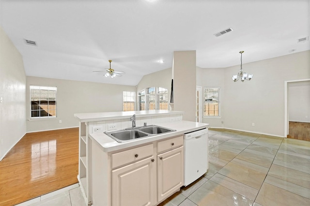 kitchen with ceiling fan with notable chandelier, white dishwasher, a kitchen island with sink, sink, and white cabinetry