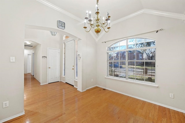 spare room with crown molding, wood-type flooring, vaulted ceiling, and an inviting chandelier