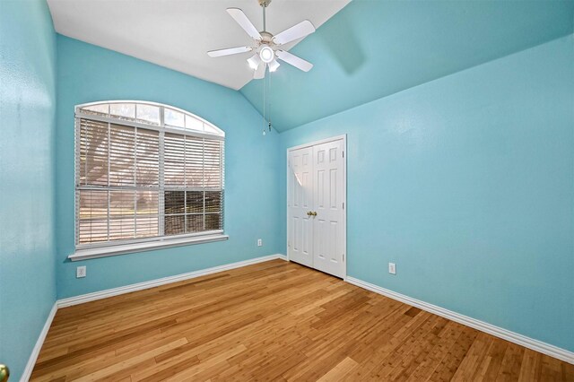 empty room featuring ceiling fan, a healthy amount of sunlight, vaulted ceiling, and light wood-type flooring