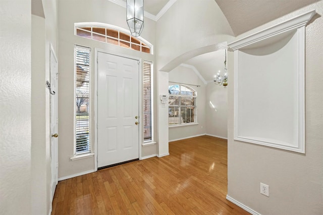 foyer with hardwood / wood-style floors, a healthy amount of sunlight, lofted ceiling, and a notable chandelier