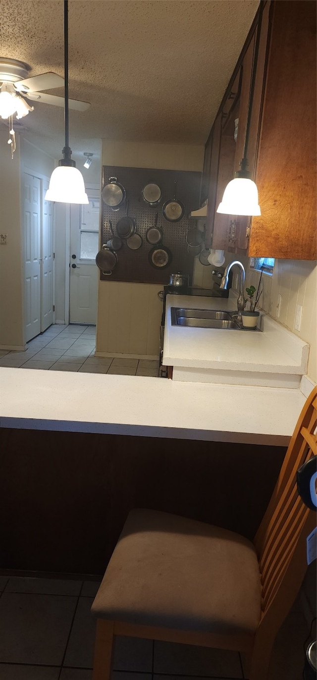 kitchen with light tile patterned floors, a textured ceiling, ceiling fan, and sink