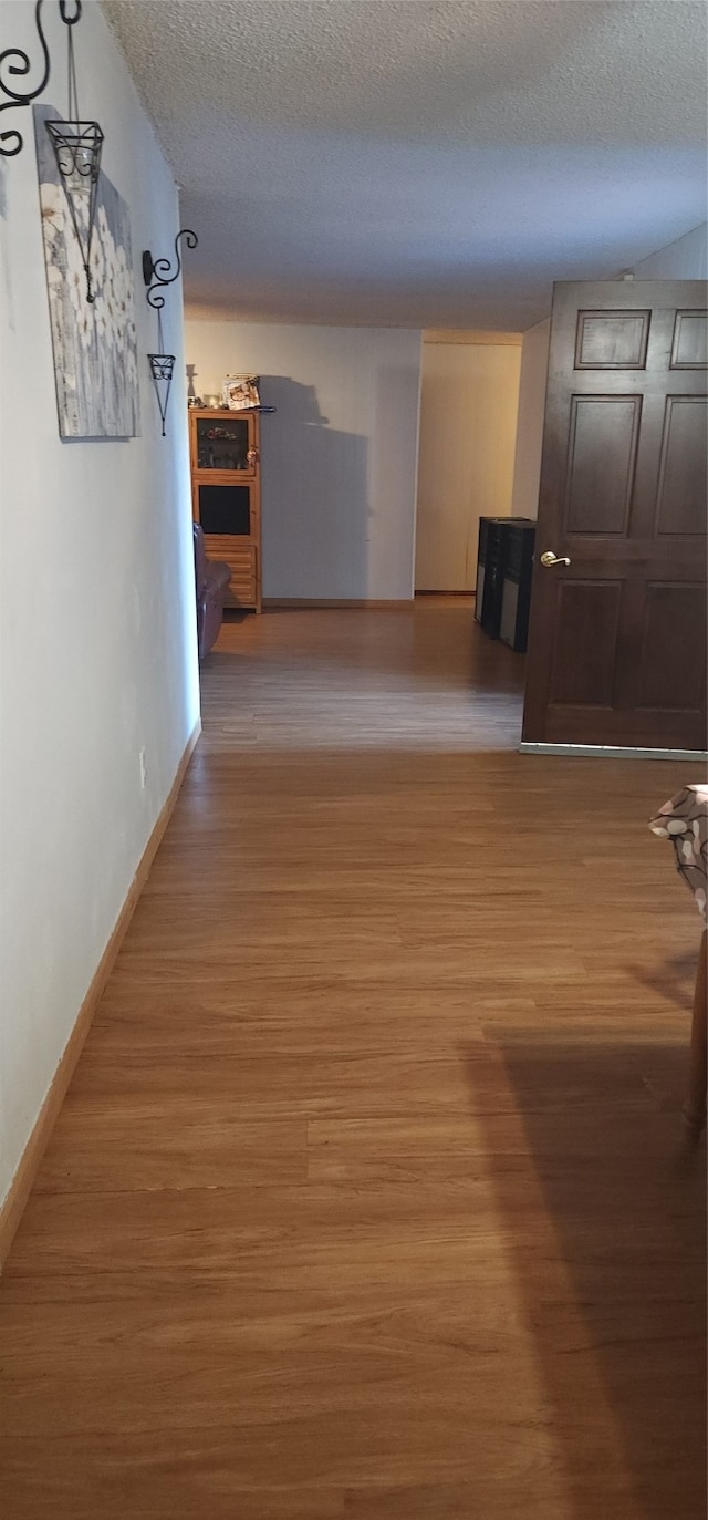 hallway featuring wood-type flooring and a textured ceiling