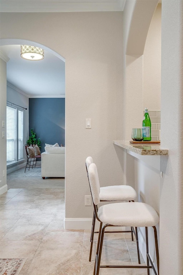 dining area with indoor bar and ornamental molding