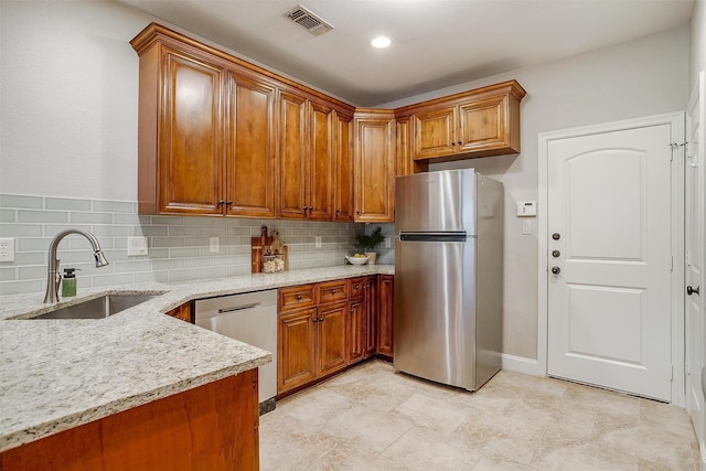 kitchen with light stone counters, stainless steel appliances, sink, and tasteful backsplash