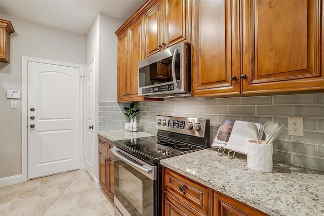 kitchen featuring light stone counters, appliances with stainless steel finishes, and backsplash