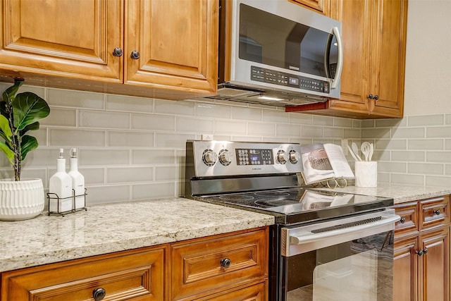 kitchen with stainless steel appliances, backsplash, and light stone counters