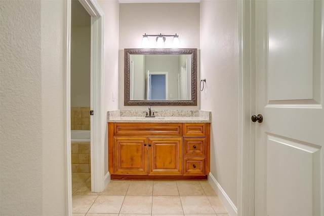 bathroom featuring tiled tub, vanity, and tile patterned floors