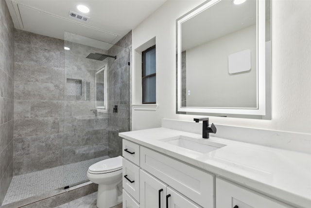 bathroom featuring tiled shower, vanity, and toilet