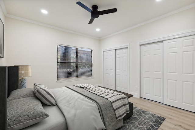 bedroom with light hardwood / wood-style floors, crown molding, ceiling fan, and multiple closets