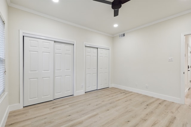 unfurnished bedroom featuring light hardwood / wood-style flooring, ceiling fan, and multiple closets