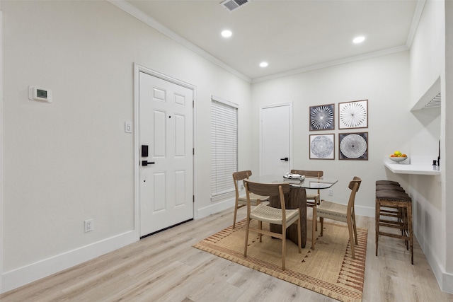 dining room with light hardwood / wood-style flooring and crown molding