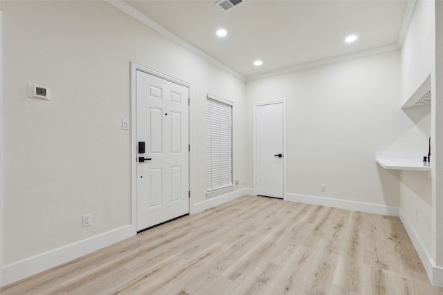 foyer with ornamental molding and light hardwood / wood-style flooring