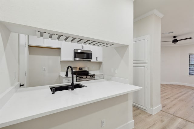 kitchen with sink, kitchen peninsula, light hardwood / wood-style floors, white cabinets, and appliances with stainless steel finishes