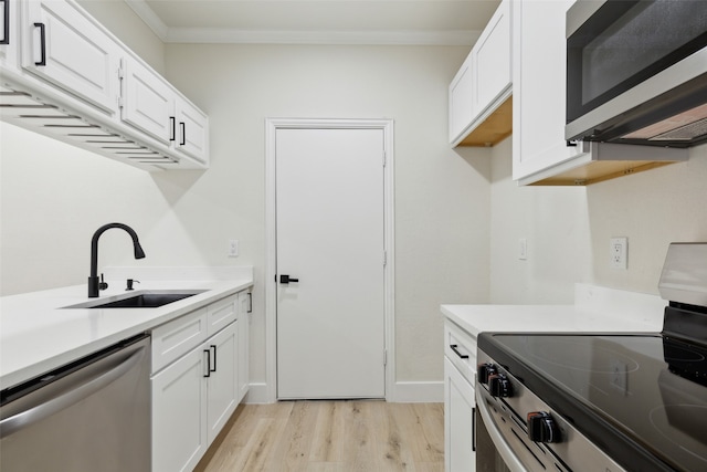 kitchen featuring white cabinets, appliances with stainless steel finishes, light wood-type flooring, and sink