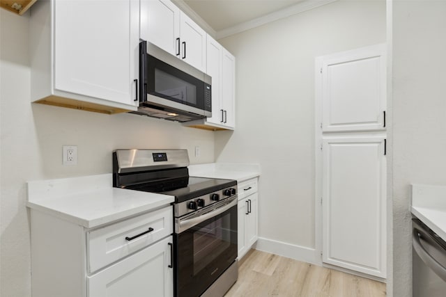 kitchen featuring ornamental molding, white cabinets, light wood-type flooring, and appliances with stainless steel finishes