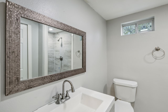 bathroom with tiled shower, vanity, and toilet