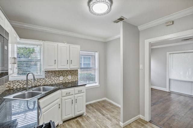 kitchen with decorative backsplash, white cabinetry, sink, and light hardwood / wood-style floors