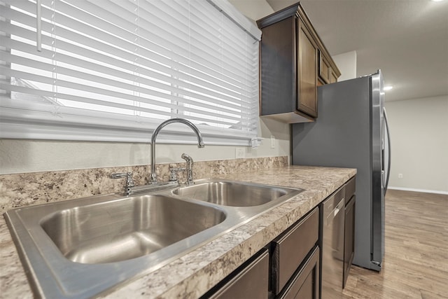 kitchen with dark brown cabinets, light hardwood / wood-style floors, sink, and stainless steel appliances