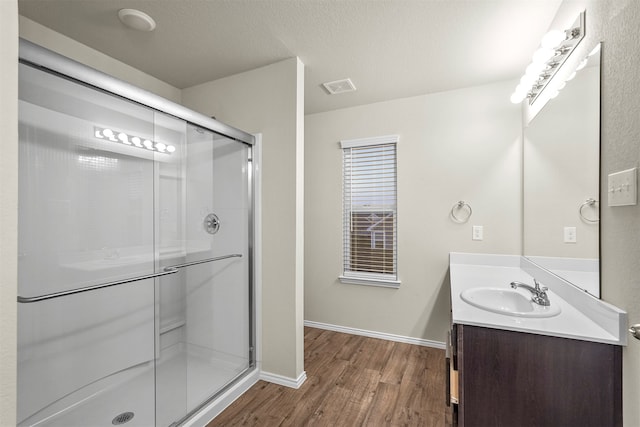 bathroom with hardwood / wood-style floors, vanity, a textured ceiling, and a shower with door