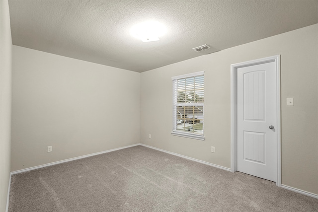 empty room with carpet floors and a textured ceiling