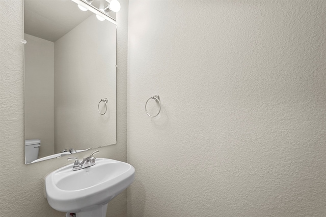 bathroom with toilet, lofted ceiling, and sink