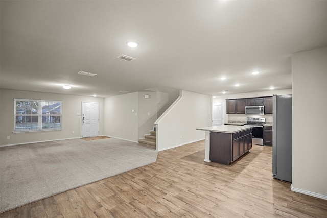 kitchen featuring dark brown cabinetry, stainless steel appliances, light hardwood / wood-style flooring, and a kitchen island