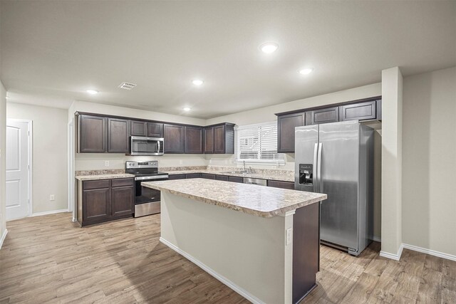 kitchen with a kitchen island, dark brown cabinetry, light hardwood / wood-style floors, and stainless steel appliances