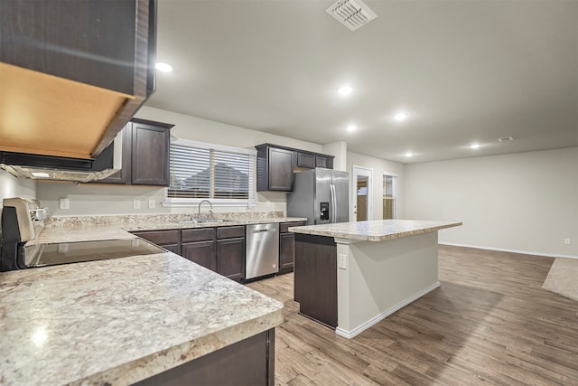 kitchen with dark brown cabinetry, sink, a center island, light hardwood / wood-style floors, and appliances with stainless steel finishes