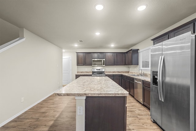 kitchen featuring a kitchen island, dark brown cabinetry, light hardwood / wood-style floors, and appliances with stainless steel finishes