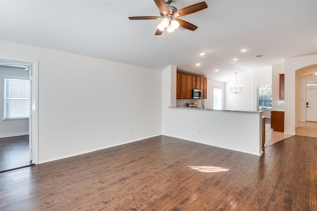 unfurnished living room with ceiling fan and dark wood-type flooring