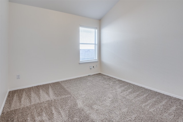 carpeted spare room with lofted ceiling