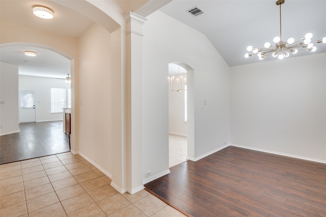 interior space featuring lofted ceiling, ceiling fan with notable chandelier, and decorative columns