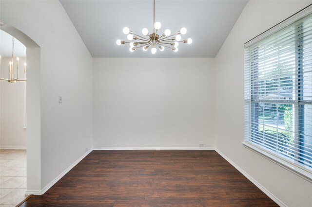 unfurnished room with dark wood-type flooring, a wealth of natural light, and a chandelier