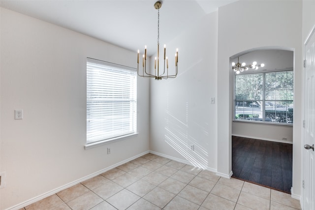 unfurnished dining area with an inviting chandelier, a wealth of natural light, and light tile patterned flooring